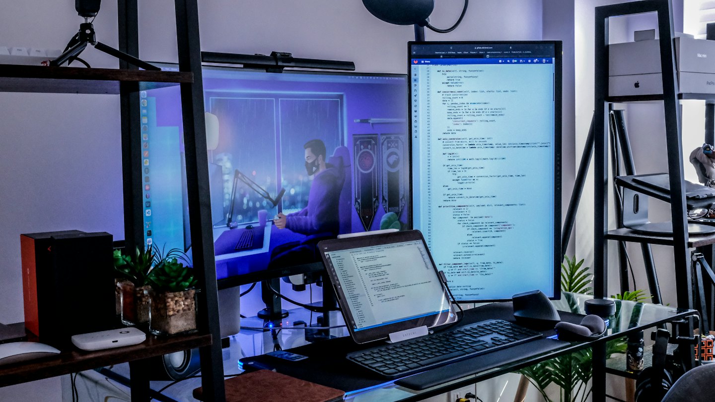 Computer screens displaying code on a organized glass desk.